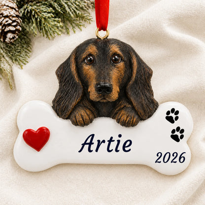 Personalized Black & Tan Dachshund Dog Bone christmas ornament laid on a soft white knit blanket