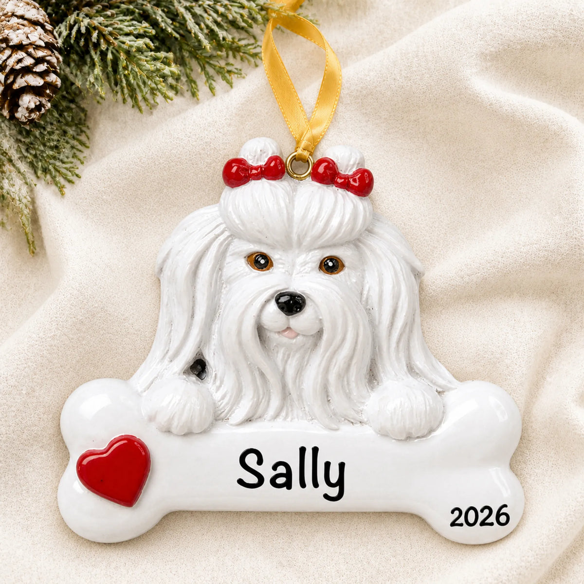 Personalized Maltese dog bone Christmas ornament resting on a soft white blanket with pine and pinecones