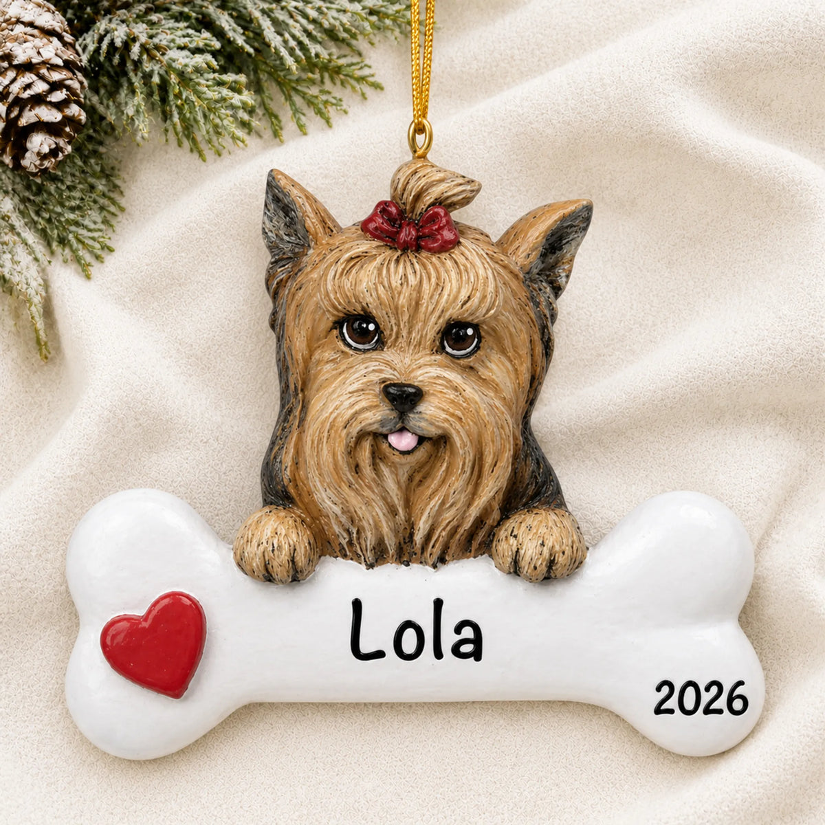Personalized Yorkie dog bone Christmas ornament resting on a soft white blanket with pine and pinecones