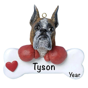 Personalized Boxer Christmas ornament, the dog resting its head and paws on a white dog bone with a red heart, the pet name laser engraved across the bone and the year below it
