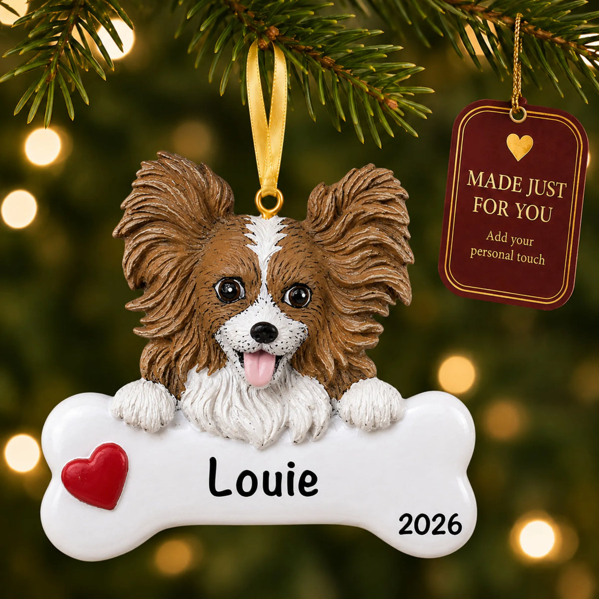 Personalized papillon Christmas ornament hanging on a lit tree beside a Made Just For You tag