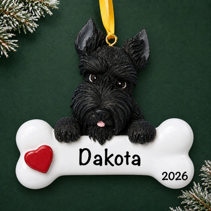 Personalized Scottie dog bone Christmas ornament, engraved with a name and year, on a green holiday backdrop