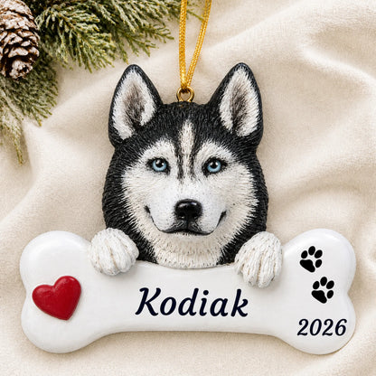 Personalized Siberian husky dog bone Christmas ornament resting on a soft white blanket with pine and pinecones