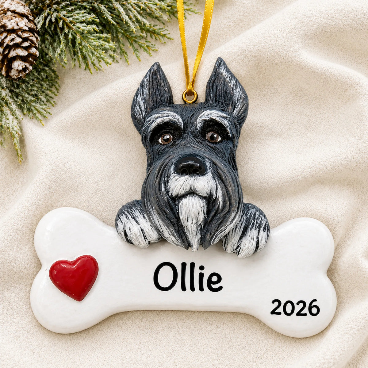 Personalized schnauzer dog bone Christmas ornament resting on a soft white blanket with pine and pinecones