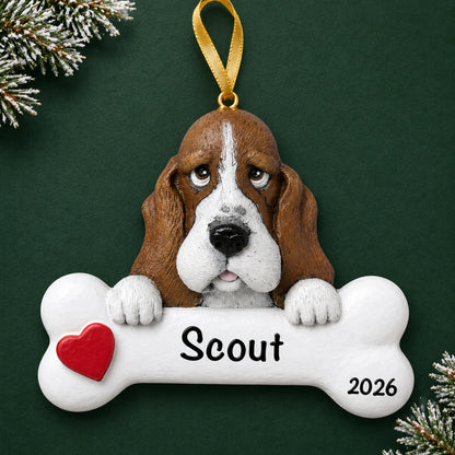 Personalized basset hound dog bone Christmas ornament, engraved with a name and year, on a green holiday backdrop
