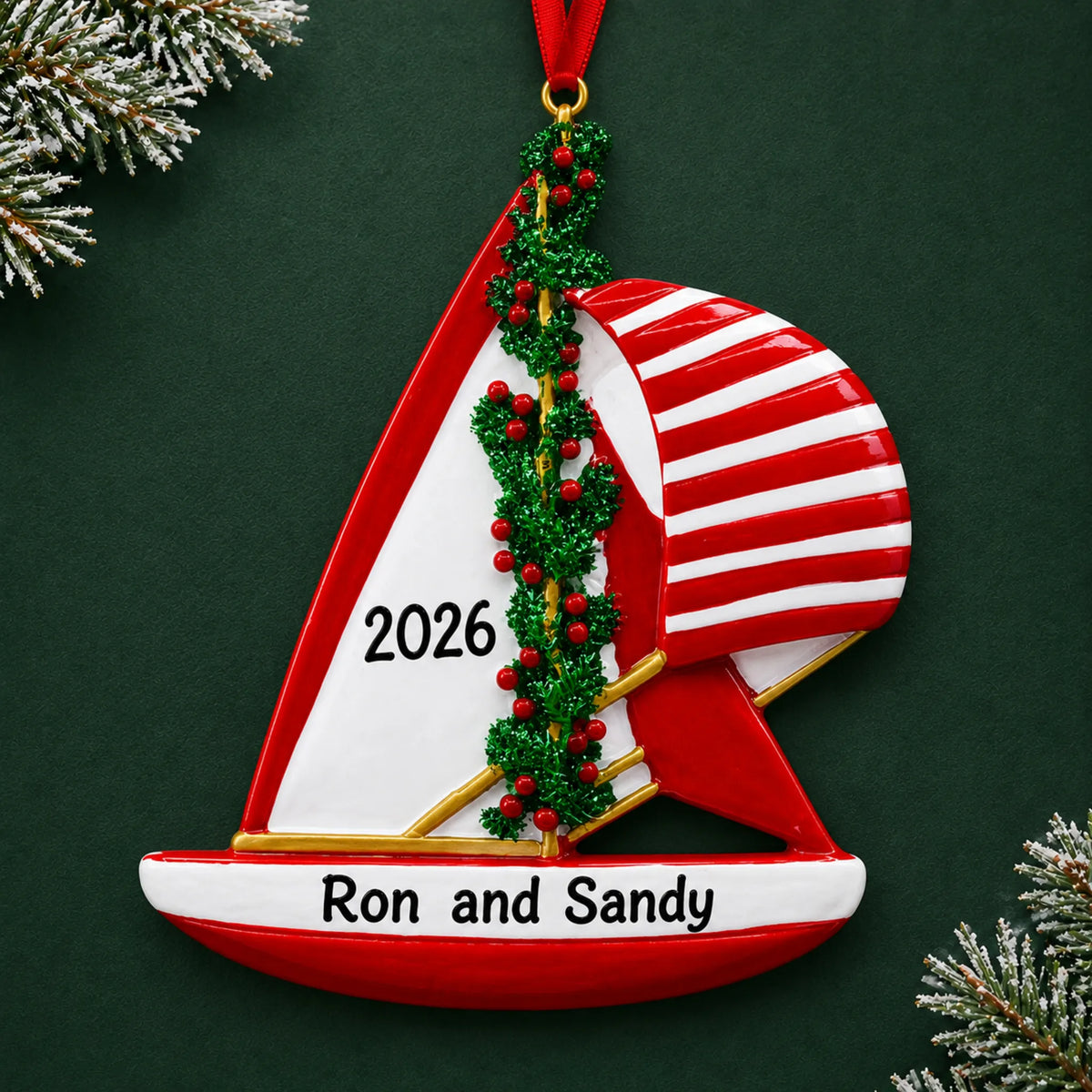 Personalized red sailboat christmas ornament on a dark green pine background