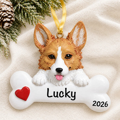 Personalized corgi dog bone Christmas ornament resting on a soft white blanket with pine and pinecones