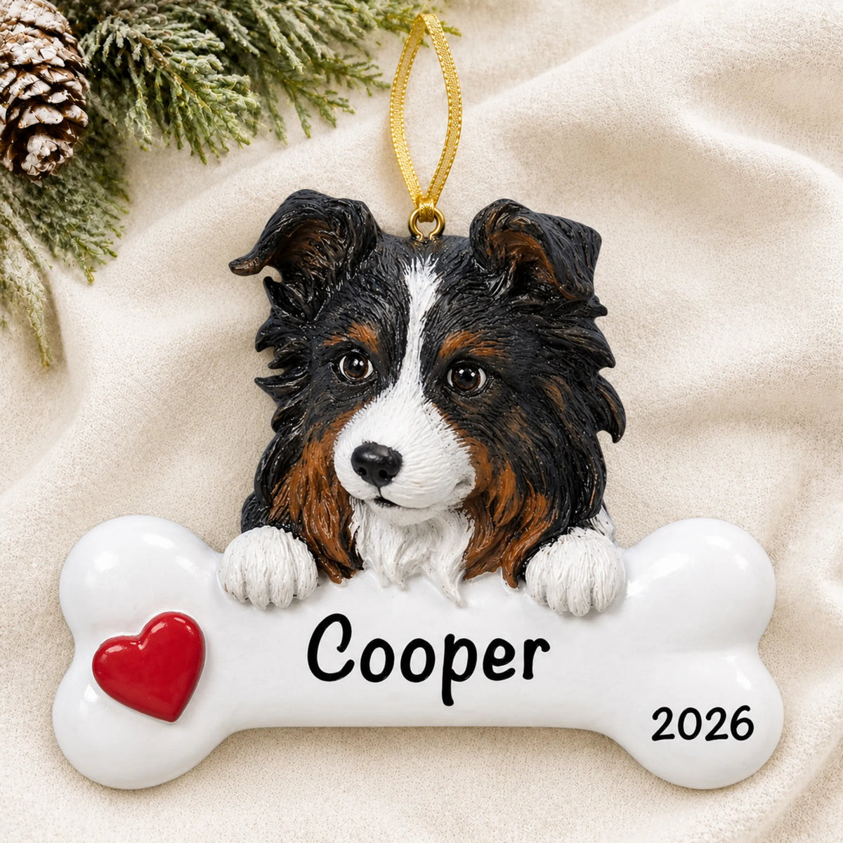 Personalized Australian shepherd dog bone Christmas ornament resting on a soft white blanket with pine and pinecones