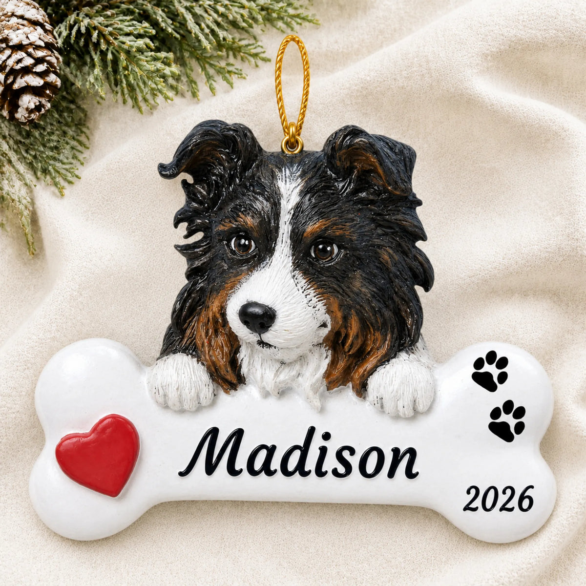 Personalized Australian Shepherd Dog Bone christmas ornament laid on a soft white knit blanket