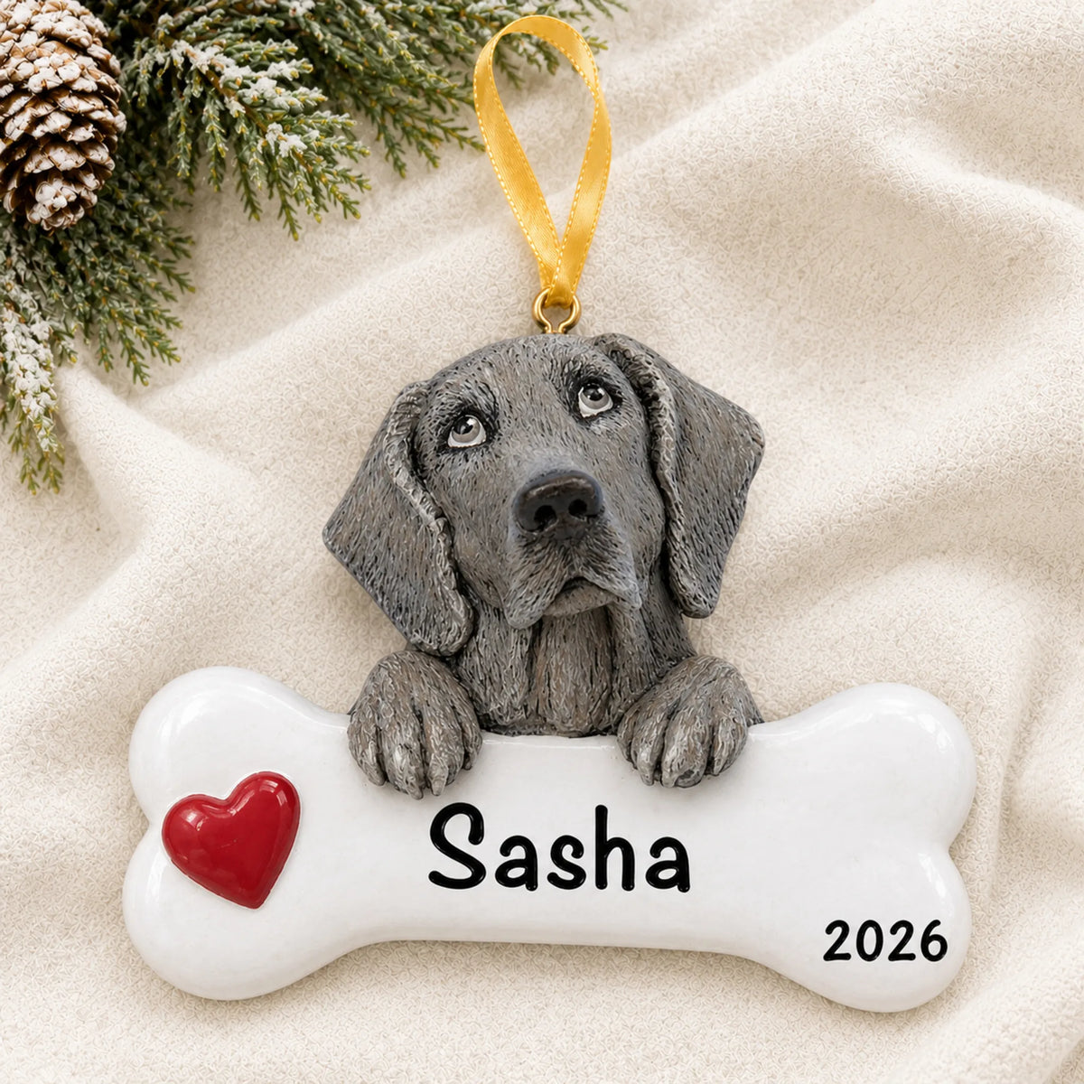 Personalized Weimaraner dog bone Christmas ornament resting on a soft white blanket with pine and pinecones