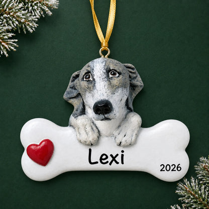 Personalized greyhound dog bone Christmas ornament, engraved with a name and year, on a green holiday backdrop
