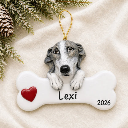 Personalized greyhound dog bone Christmas ornament resting on a soft white blanket with pine and pinecones