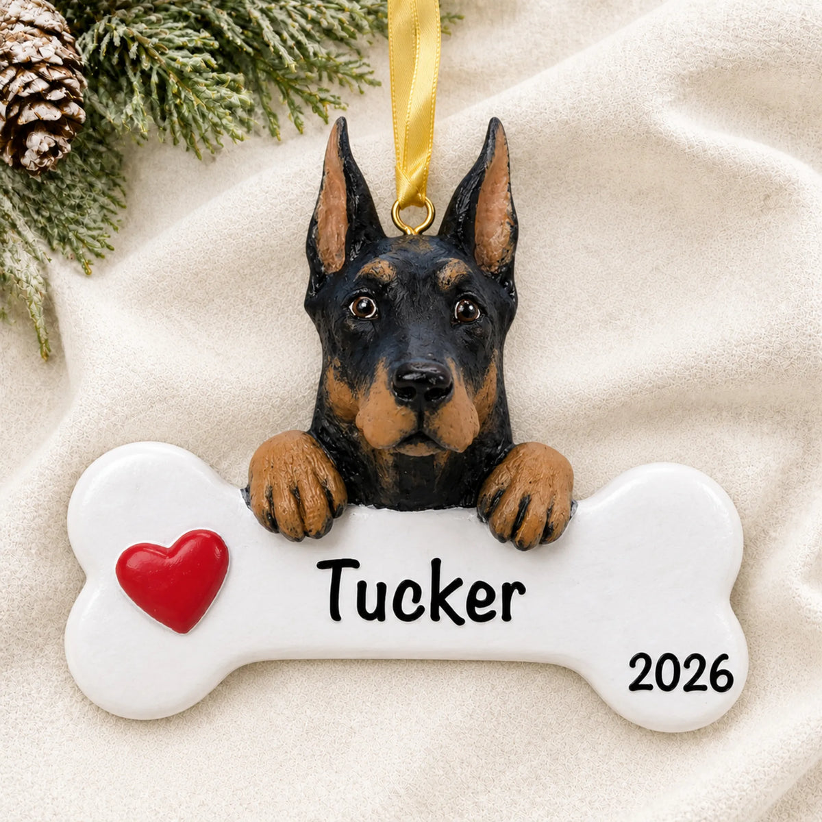 Personalized Doberman pinscher dog bone Christmas ornament resting on a soft white blanket with pine and pinecones