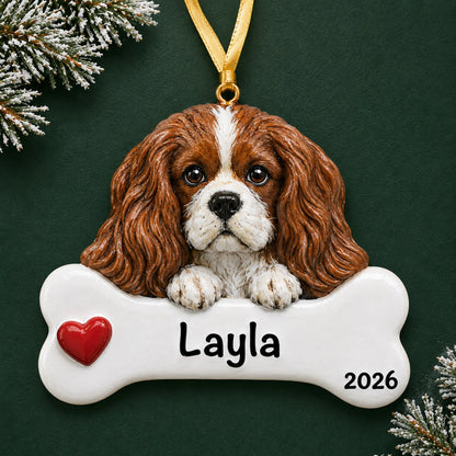 Personalized King Charles Cavalier dog bone Christmas ornament, engraved with a name and year, on a green holiday backdrop