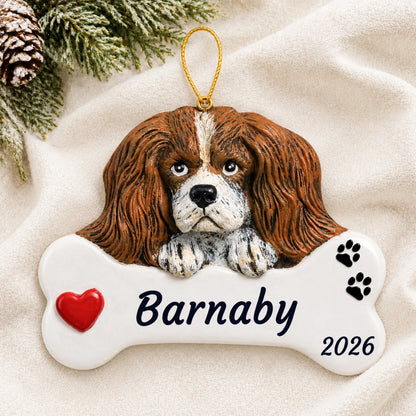 Personalized King Charles Cavalier Dog Bone christmas ornament laid on a soft white knit blanket