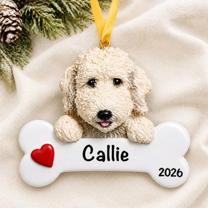 Personalized Labradoodle dog bone Christmas ornament resting on a soft white blanket with pine and pinecones