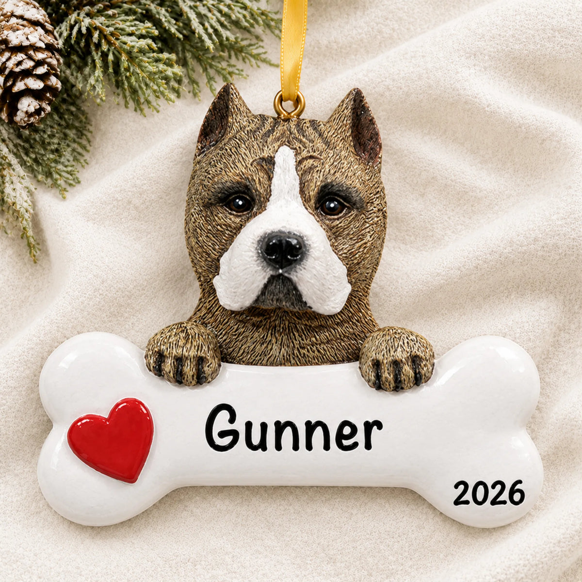 Personalized pit bull dog bone Christmas ornament resting on a soft white blanket with pine and pinecones