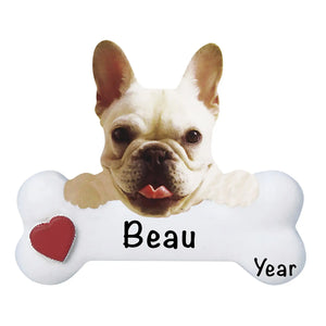 Personalized French Bulldog Christmas ornament, the dog resting its head and paws on a white dog bone with a red heart, the pet name laser engraved across the bone and the year below it