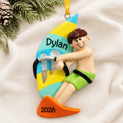 Personalized windsurfing guy christmas ornament laid on a soft white knit blanket