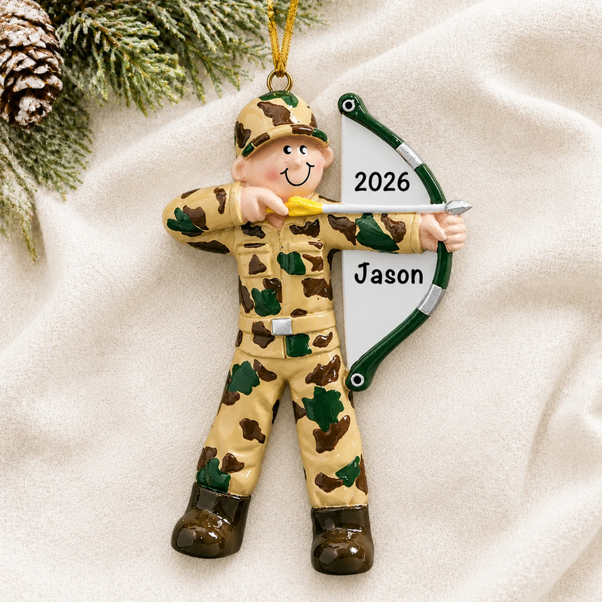 Personalized hunter bow & arrow christmas ornament laid on a soft white knit blanket
