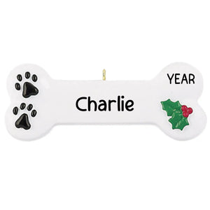 Personalized white dog bone Christmas ornament with black paw prints and holly, engraved with a name and year