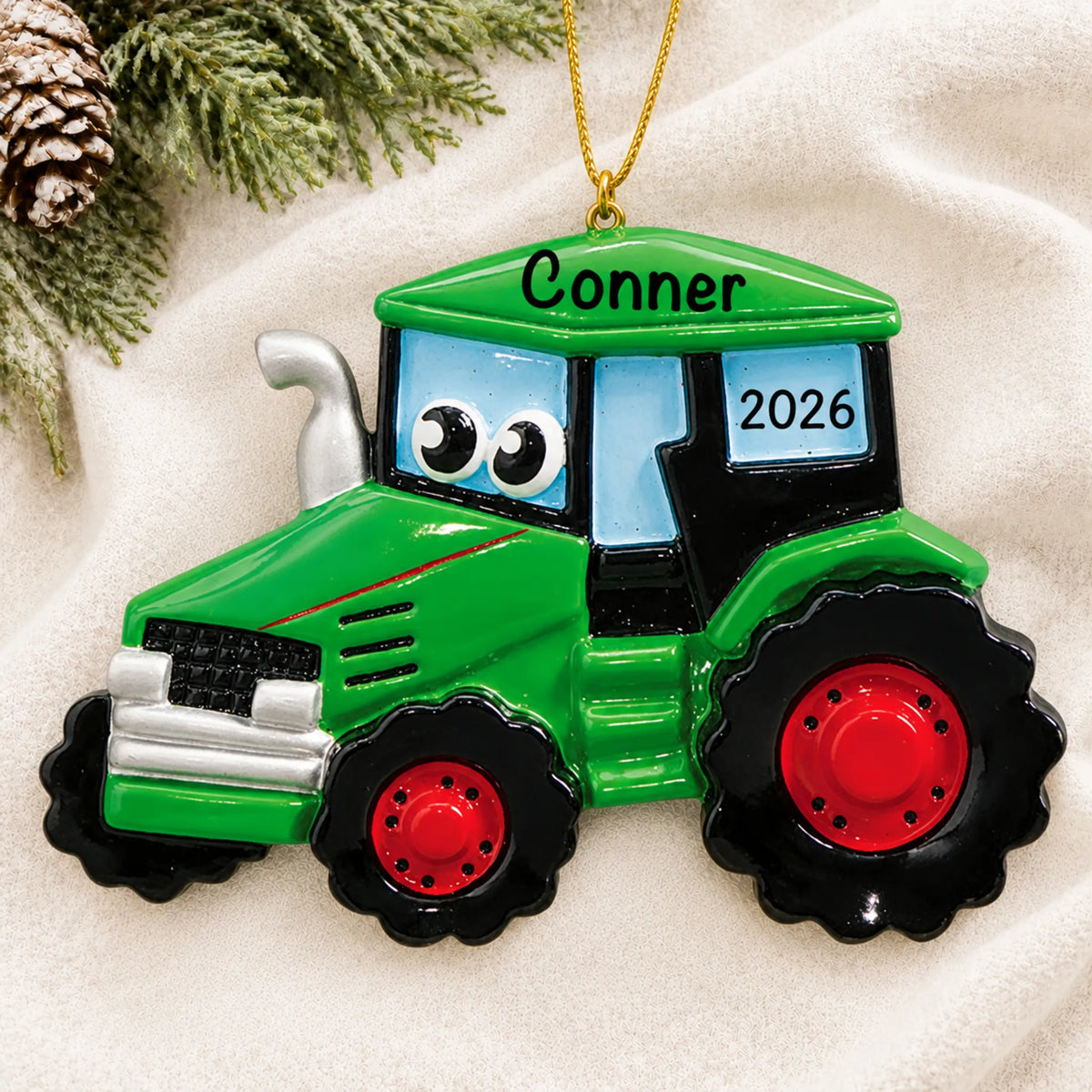 Personalized green tractor christmas ornament laid on a soft white knit blanket