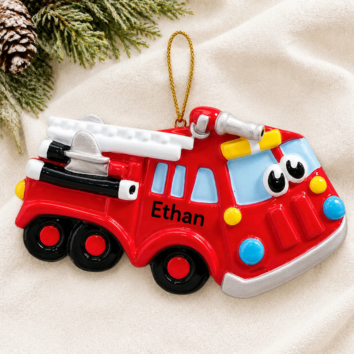 Personalized fire truck christmas ornament laid on a soft white knit blanket