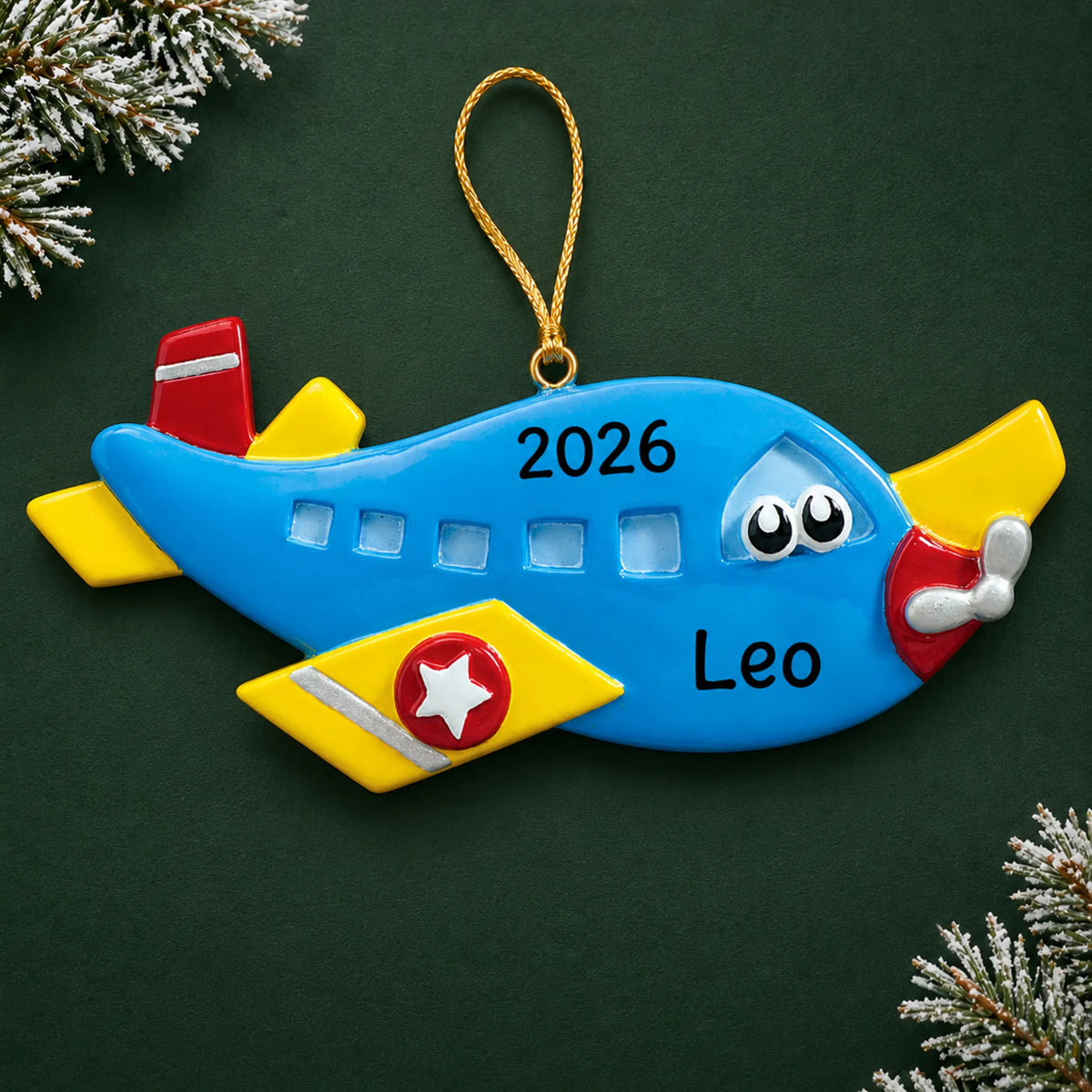 Personalized blue airplane christmas ornament on a dark green pine background