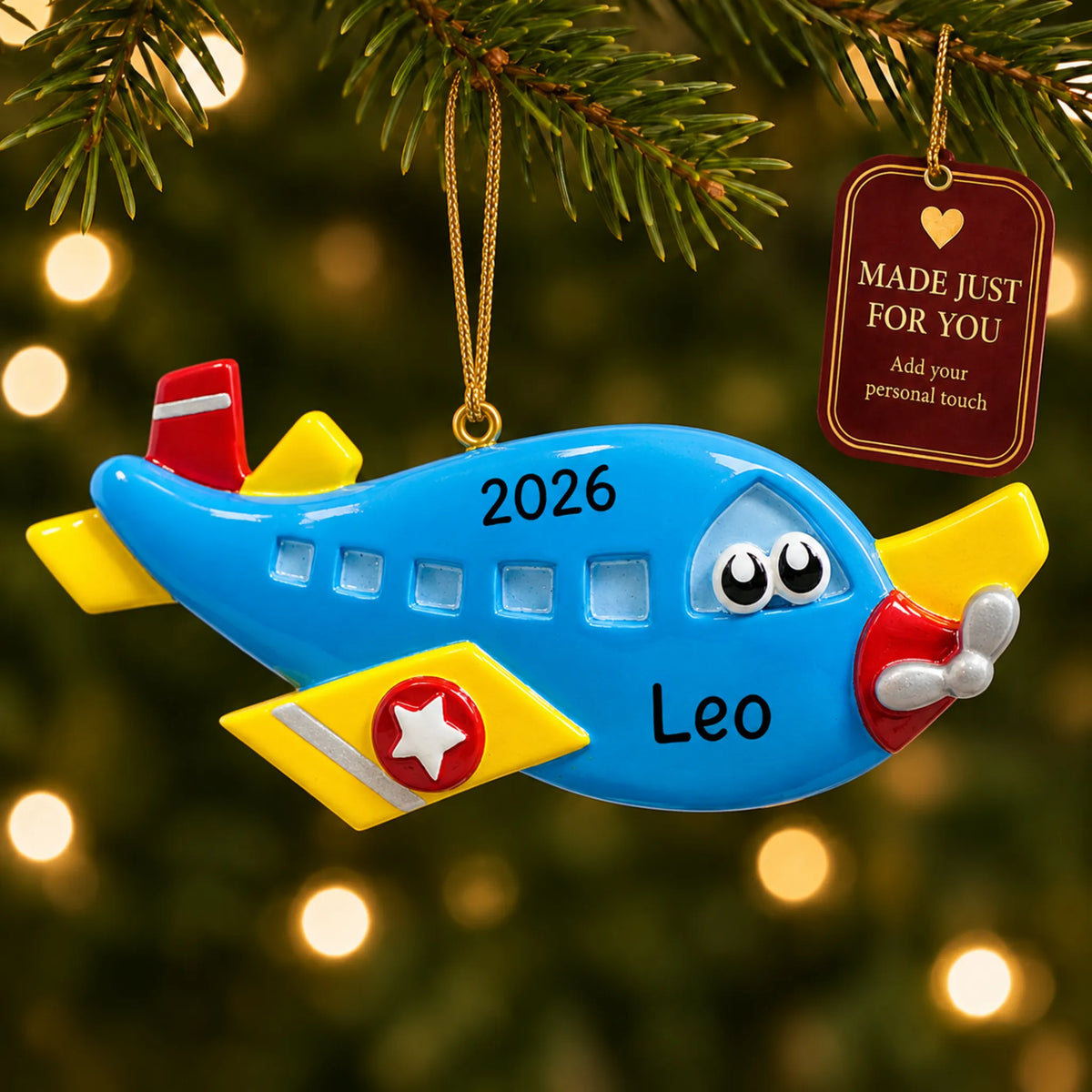 Blue airplane christmas ornament hanging on a lit Christmas tree with a Made Just For You gift tag