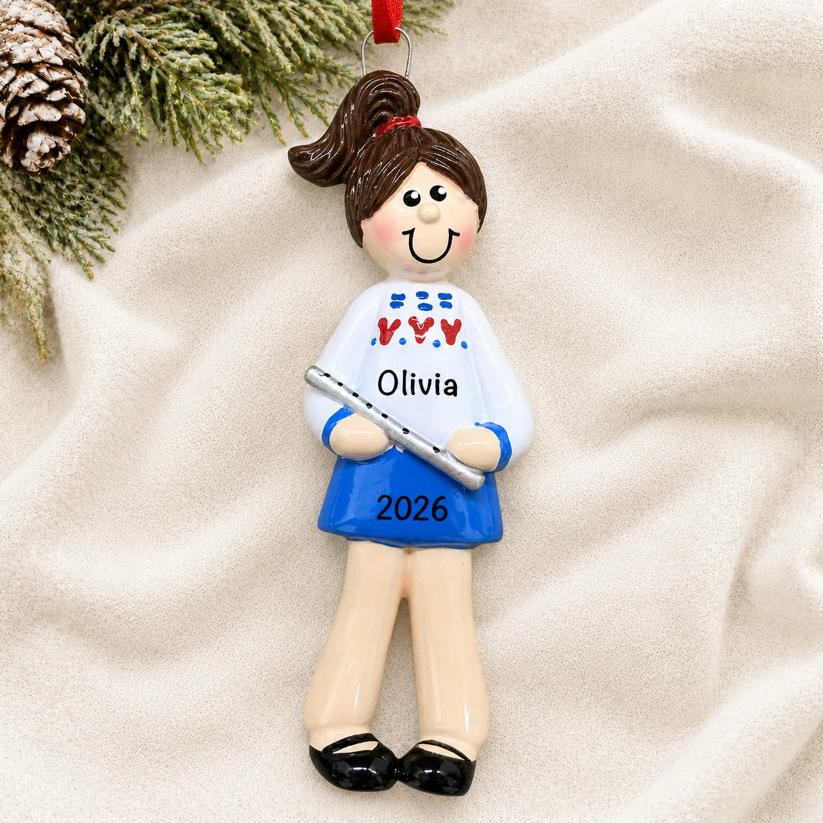 Personalized flute girl christmas ornament laid on a soft white knit blanket