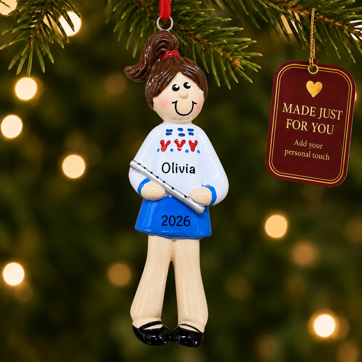 Flute girl christmas ornament hanging on a lit Christmas tree with a Made Just For You gift tag