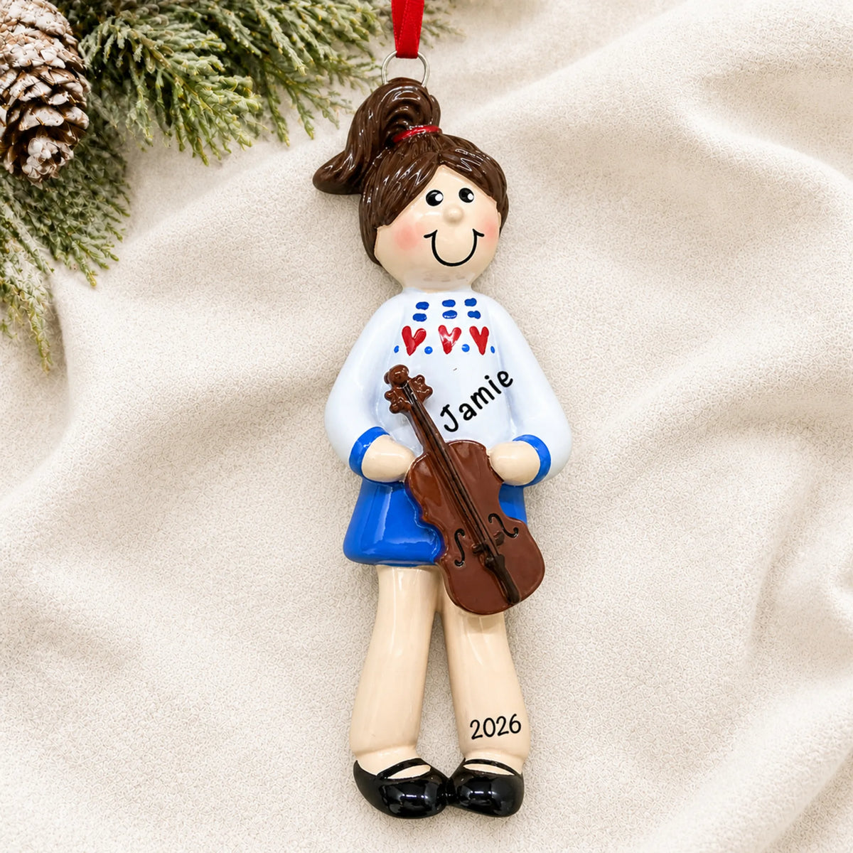 Personalized violin girl christmas ornament laid on a soft white knit blanket