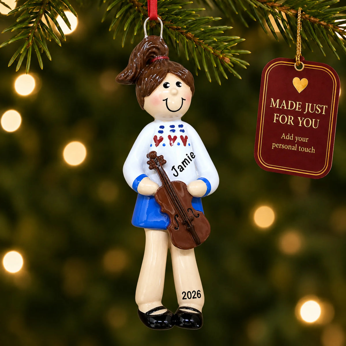 Violin girl christmas ornament hanging on a lit Christmas tree with a Made Just For You gift tag