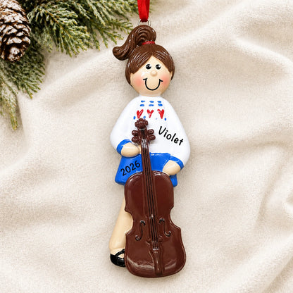 Personalized cello girl christmas ornament laid on a soft white knit blanket