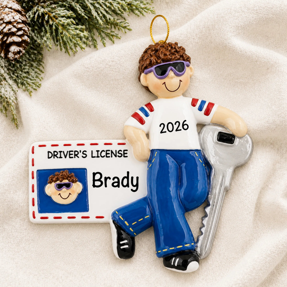 Personalized new driver's license brunette boy christmas ornament laid on a soft white knit blanket
