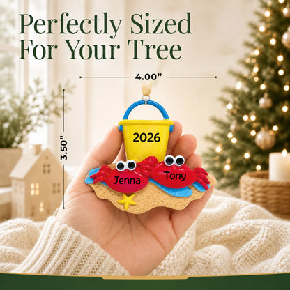 Size guide: the personalized crab couple beach christmas ornament is 4.00 in wide by 3.50 in tall, shown in hand