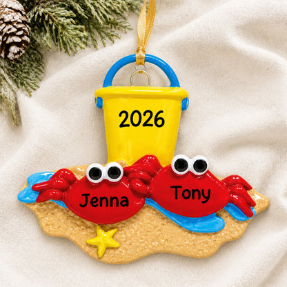 Personalized crab couple beach christmas ornament laid on a soft white knit blanket