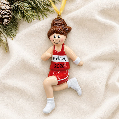 Personalized track girl runner christmas ornament laid on a soft white knit blanket