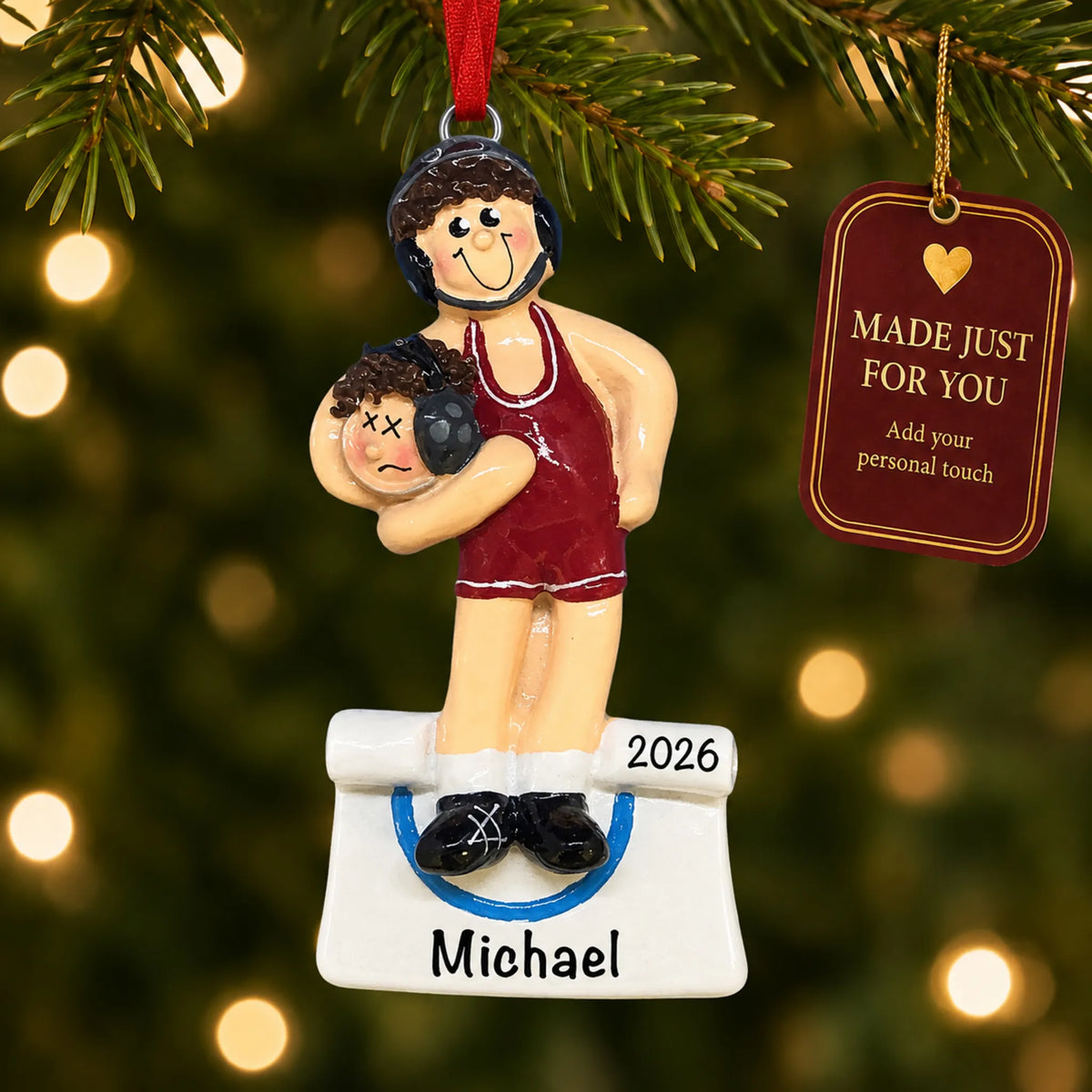 Male wrestler in a red singlet christmas ornament hanging on a lit Christmas tree with a Made Just For You gift tag