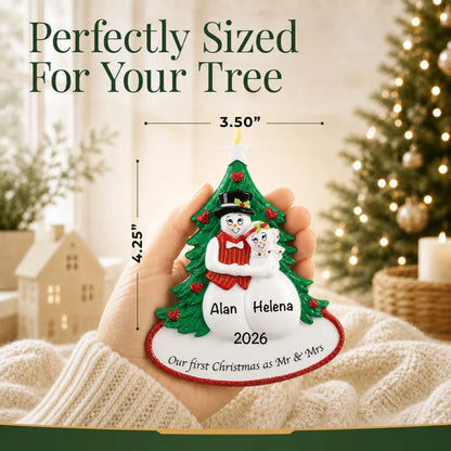 Personalized newlywed snow couple Christmas ornament held in a hand to show its 3.5 by 4.25 inch size