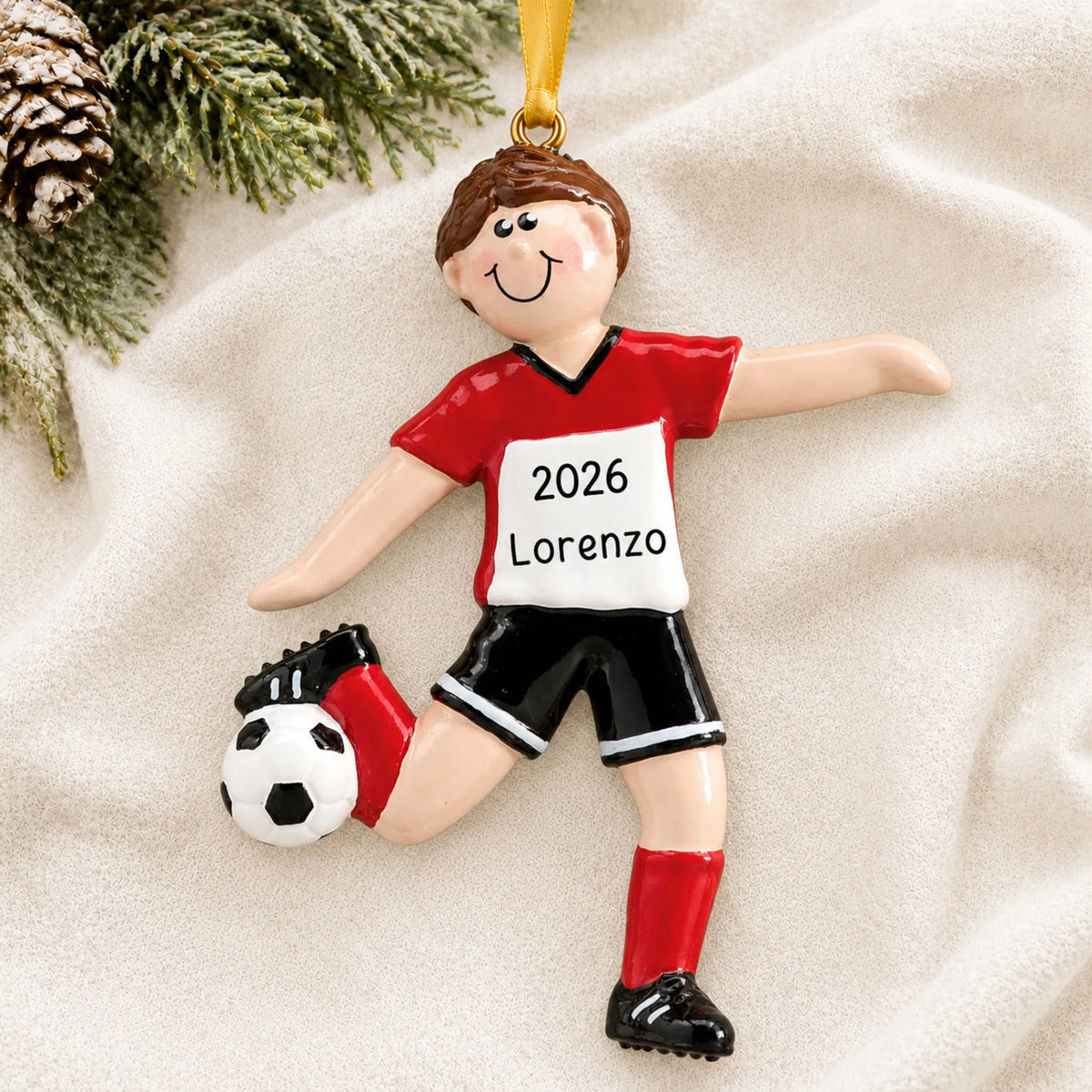 Personalized brunette soccer guy christmas ornament laid on a soft white knit blanket