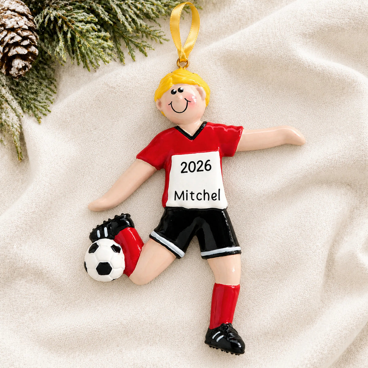 Personalized blonde soccer guy christmas ornament laid on a soft white knit blanket