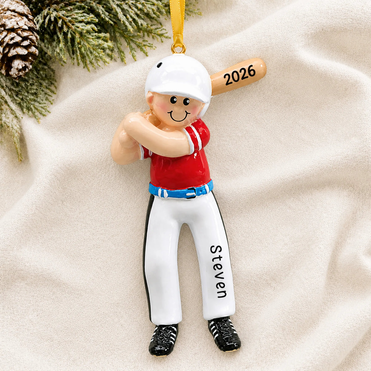 Personalized baseball boy batter christmas ornament laid on a soft white knit blanket