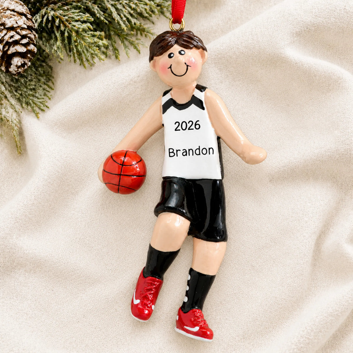 Personalized basketball boy christmas ornament laid on a soft white knit blanket