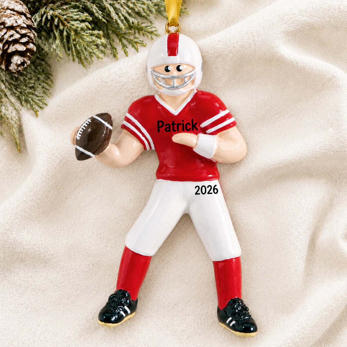 Personalized football boy christmas ornament laid on a soft white knit blanket