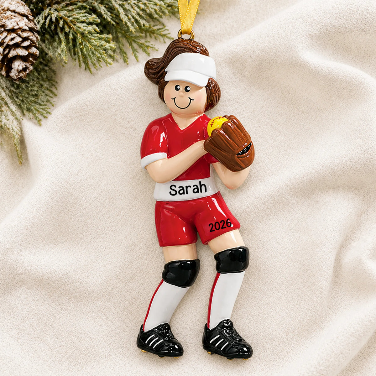 Personalized softball girl christmas ornament laid on a soft white knit blanket