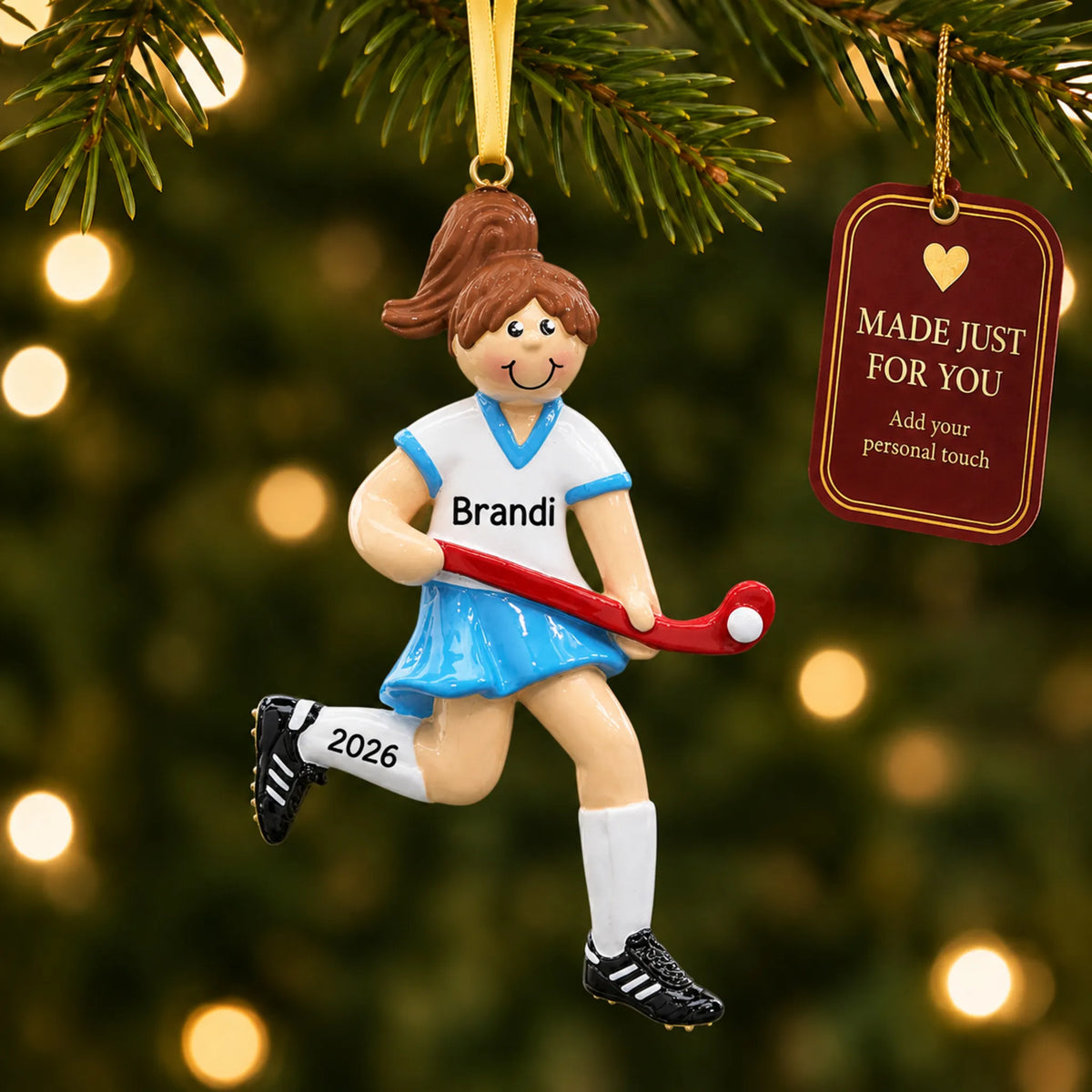 Field hockey girl christmas ornament hanging on a lit Christmas tree with a Made Just For You gift tag