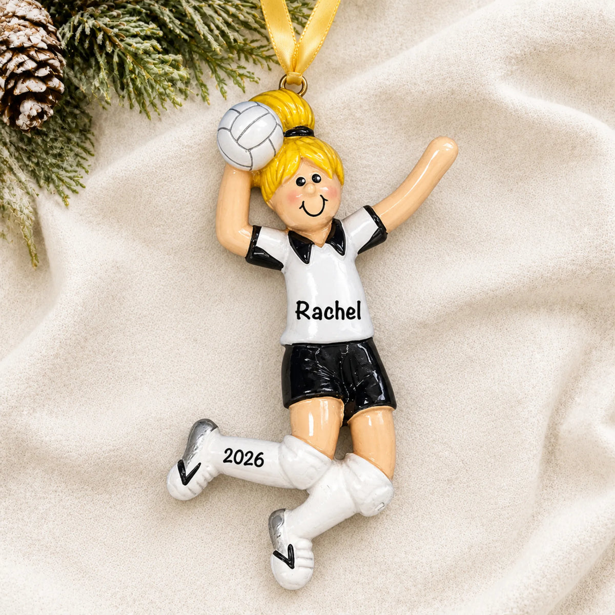 Personalized blonde volleyball girl christmas ornament laid on a soft white knit blanket