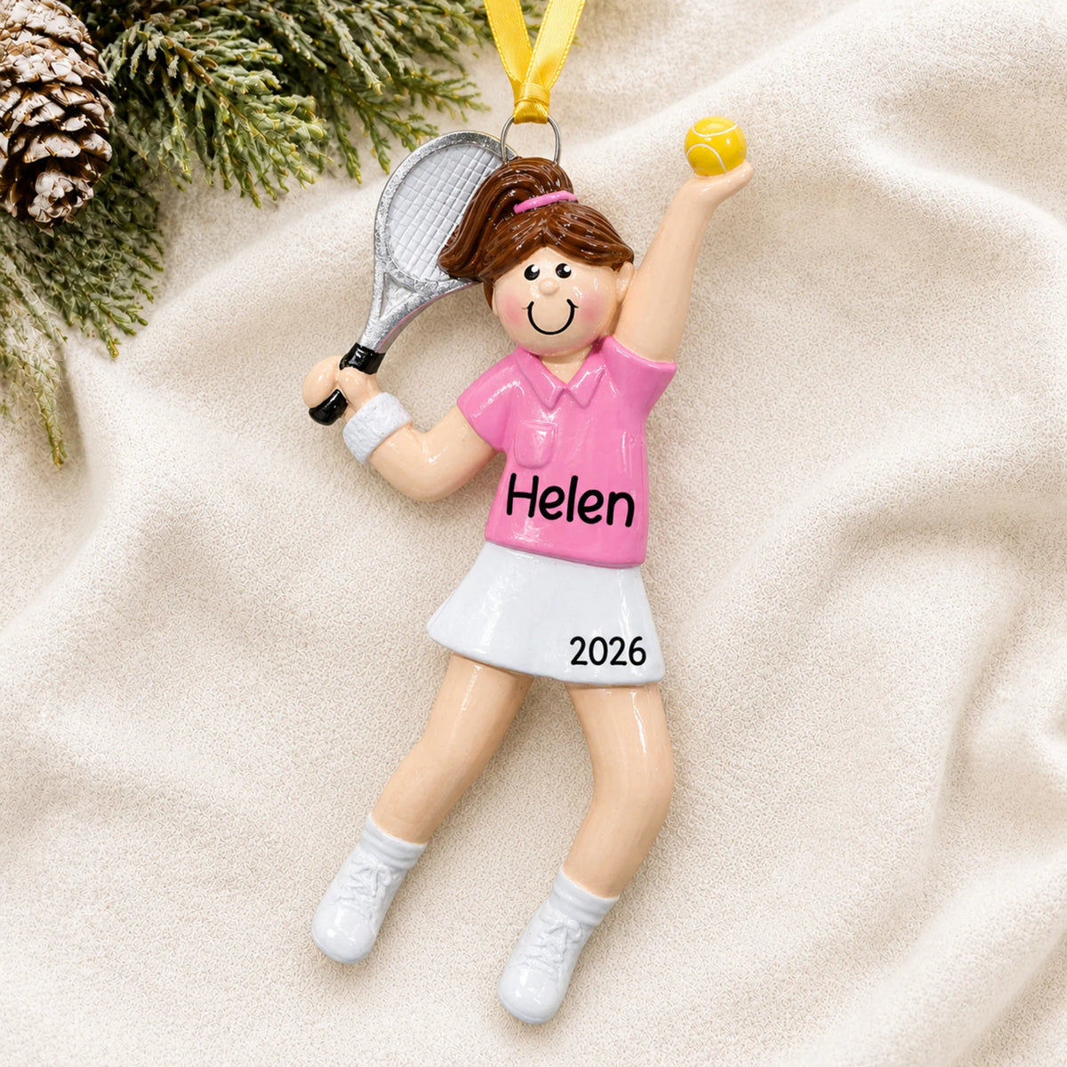 Personalized tennis girl christmas ornament laid on a soft white knit blanket