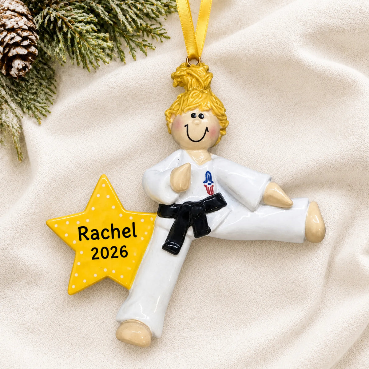 Personalized blonde karate girl christmas ornament laid on a soft white knit blanket